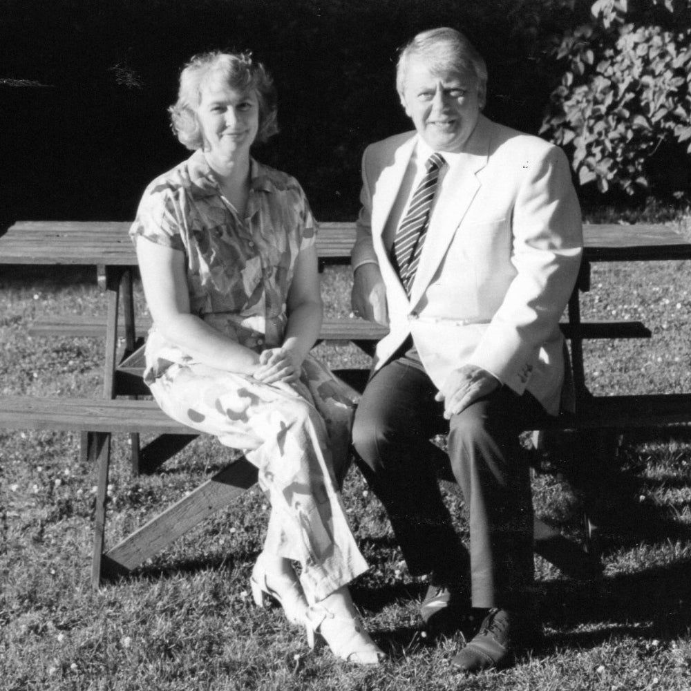 Two people sitting on a bench outdoors in black and white.